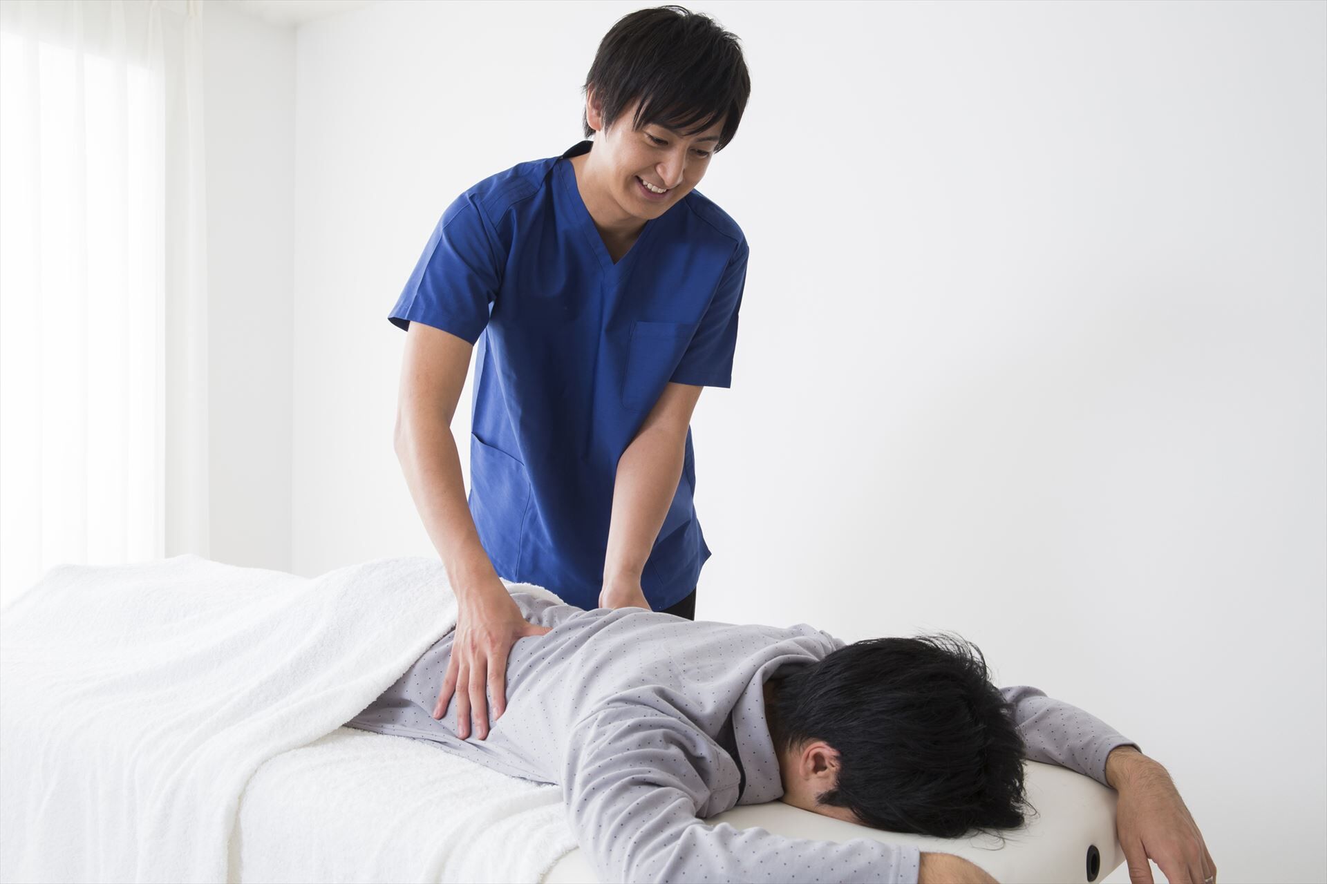 男性の腰を施術するスタッフ